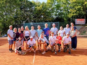Teilnehmerinnen und Teilnehmer der Saisonabschlussfeier des TC Blau-Weiß Gelnhausen mit Tennisschlägern auf dem Tennisplatz.