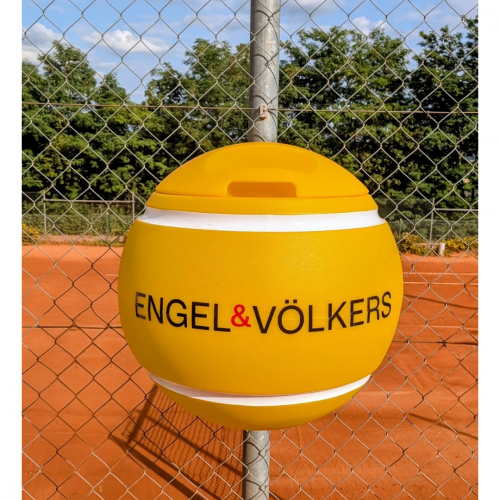 Gelber tennisballförmiger Mülleimer von Engel & Völkers auf einem Sandplatz