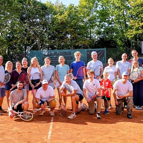 Teilnehmerinnen und Teilnehmer der Saisonabschlussfeier des TC Blau-Weiß Gelnhausen mit Tennisschlägern auf dem Tennisplatz.